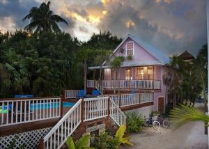 una casa rosa con una piscina frente a ella en Barbara's Beach House, en Caye Caulker