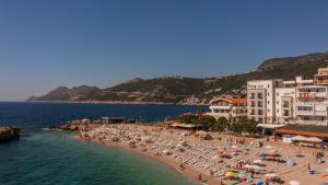 a beach with umbrellas and people on the water at Apartments Atlantis in Dobra Voda