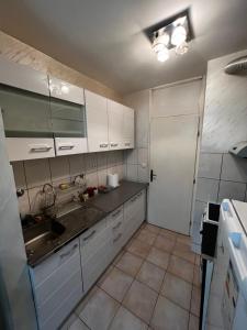 - une cuisine avec des placards blancs et un évier dans l'établissement GOLD APARTMENT, à Berane