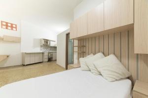 1 dormitorio con 1 cama blanca grande y cocina en Loft Urbano en Medellín Pet Friendly 105, en Medellín