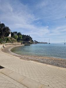 a beach with a person sitting on a bench next to the water at Villa Porta Krk in Krk