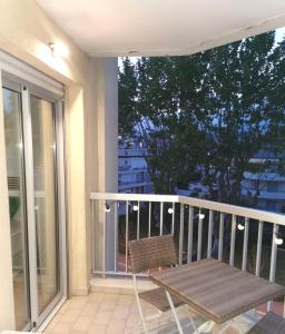 a wooden chair sitting on a balcony with a table at Lido, private apartment seaside, parking, swimming pool in Cagnes-sur-Mer