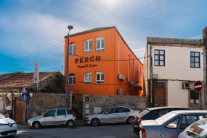 Peach Hostel & Suites في بورتو: مبنى برتقالي مع سيارات تقف في موقف للسيارات