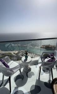 a balcony with chairs and a view of the ocean at برج داماك الكورنيش الجناح اليوناني Damac jeddah Tower in Jeddah