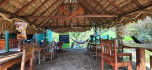 a restaurant with tables and chairs and a straw roof at La Cascada Hostel & Restaurant in Rivas