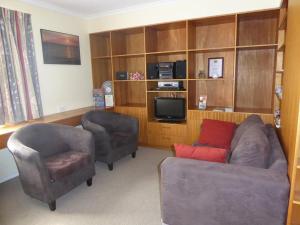 a living room with a couch and a chair and a tv at Lemontree Cottage in Kingscote