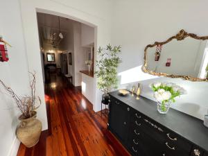 a living room with a black dresser and a mirror at La Casa Bonita Auckland in Auckland