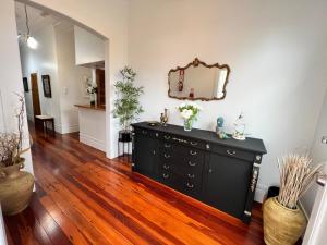 een zwarte dressoir in een woonkamer met een spiegel bij La Casa Bonita Auckland in Auckland