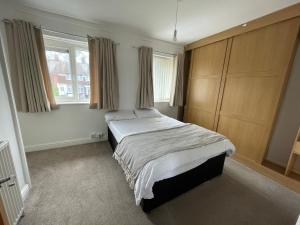 a bedroom with a bed and two windows at 2BR 15 min to BHX Airport 5 min to Heartlands in Birmingham