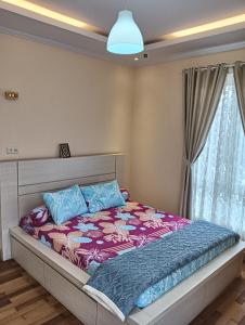 1 dormitorio con 1 cama con almohadas moradas y azules en Azizah's Syariah Homestay, en Padangluar