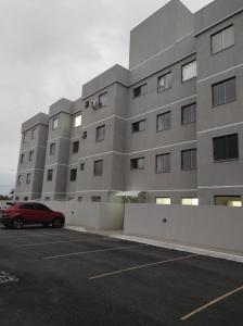 un edificio con un coche rojo estacionado en un estacionamiento en Apartamento Studio PNG novo e confortável en Paranaguá