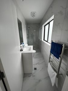 Baño blanco con lavabo y espejo en Modern Home by the Reserve, en Auckland