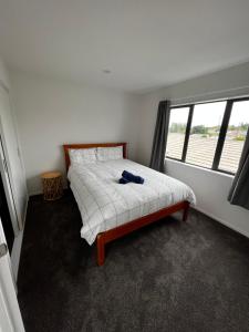 um quarto com uma cama e uma janela em Modern Home by the Reserve em Auckland