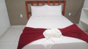 uma cama branca com um arco vermelho e branco em Pousada Maria Bonita em Paripueira