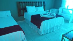 a hotel room with two beds with towels on them at Pousada Maria Bonita in Paripueira