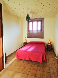 a bedroom with a red bed in a room at Casas Rurales Los Molinos in Sanlúcar de Guadiana