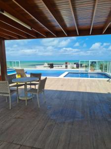 a patio with a table and chairs next to a swimming pool at Excelente FLAT 2 QTS BESSA - FLAT ALTÂNTICO NORTE in João Pessoa