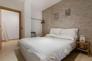 a bedroom with a large white bed with a brick wall at NEW BAZAAR Apartment in Tirana