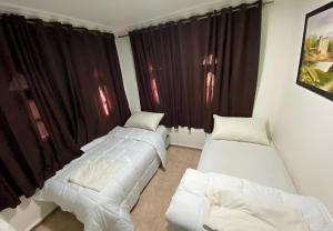 2 Betten in einem Zimmer mit schwarzen Vorhängen in der Unterkunft Villa El Ghriss in Bine el Ouidane