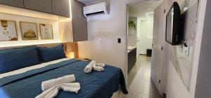 a bedroom with a blue bed with towels on it at Hamptons João Pessoal in João Pessoa