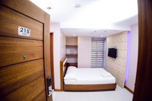 um pequeno quarto com uma cama e uma porta em coastal hotel em Iloilo