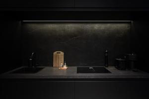 a kitchen counter with two sinks and a black wall at Arivare Cormelana in A Coruña