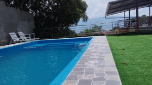 une piscine bleue avec une pelouse verte et des chaises dans l'établissement Alojamiento Los Jardines, à Lamas