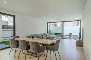 a dining room with a wooden table and chairs at SereneScape Villa - Fernão Ferro in Fernao Ferro