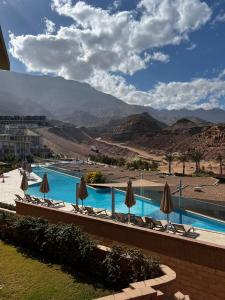 a resort with a pool with umbrellas and mountains at شاليه بقريه المونت جلاله in Ain Sokhna