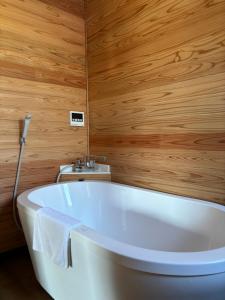 W łazience z drewnianymi ścianami znajduje się biała wanna. w obiekcie Kita Karuizawa Morino Takibi NO4 w mieście Tsumagoi