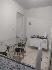 a white kitchen with a glass table and chairs at Casa em Uberaba com garagem in Uberaba