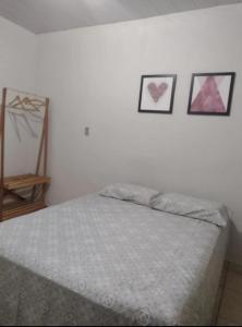 a bedroom with a bed with three pictures on the wall at Casa em Uberaba com garagem in Uberaba