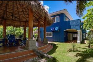 ein blaues Haus mit einer Terrasse und einem Sonnenschirm in der Unterkunft Welcome to The Beach House in Playa Pochomil