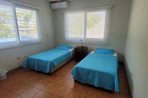 2 Betten in einem Zimmer mit 2 Fenstern in der Unterkunft Welcome to The Beach House in Playa Pochomil