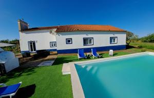 a house with a swimming pool in front of a house at Monte do Rochinha in Monte da Cardosa