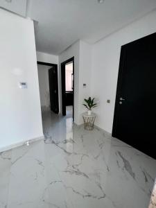un soggiorno con pavimento in marmo e porta nera di Appartement Prestigia 3 chambres a Marrakech