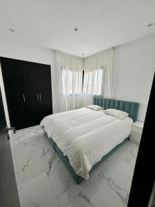 una camera bianca con un grande letto e pavimenti in marmo di Appartement Prestigia 3 chambres a Marrakech