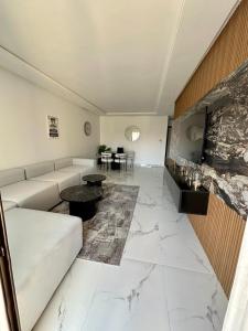 - un salon avec un canapé blanc et un sol en marbre dans l'établissement Appartement Prestigia 3 chambres, à Marrakech