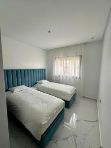 2 letti in una camera con pavimenti in marmo di Appartement Prestigia 3 chambres a Marrakech