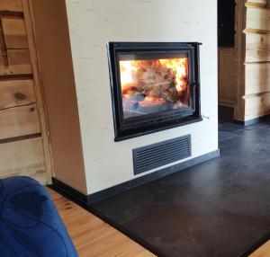 a fireplace with a fire in it in a room at Chata Wilka - całoroczny dom z bali na wyłączność z 3 sypialniami in Brzegi Dolne