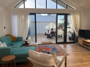 a living room with a blue couch and a tv at The Lighthouse - Boathouse Bay in Auckland