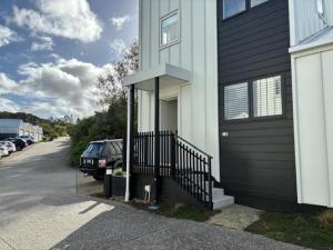 una casa en blanco y negro con un coche aparcado al lado en The Lighthouse - Boathouse Bay, en Auckland