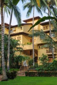 a large building with palm trees in front of it at Los Tules Ocean Front Studio 901 - 2nd floor in Puerto Vallarta