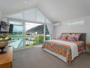 a bedroom with a bed and a large window at Villa Viti - Pauanui Holiday Home in Pauanui