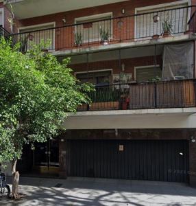 un edificio de apartamentos con balcón y un árbol en Cálido y Amplio Apartamento en Belgrano en Buenos Aires
