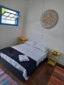 a bedroom with a bed and a window and two tables at Pousada Tabernáculo in Tiradentes