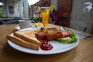 a plate of food with bacon and toast and a glass of orange juice at Griya D'Carik in Perean