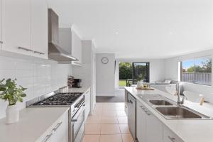 a white kitchen with a sink and a stove at Island Luxe Retreat Cowes in Cowes +23 photos