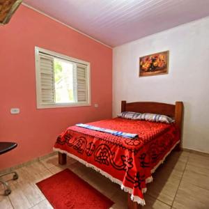 a bedroom with a bed with a redspread and a window at Estalagem Sitio Colibri in Cunha +51 photos