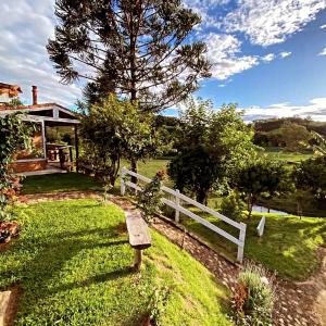 a bench sitting in the grass next to a white fence at Estalagem Sitio Colibri in Cunha